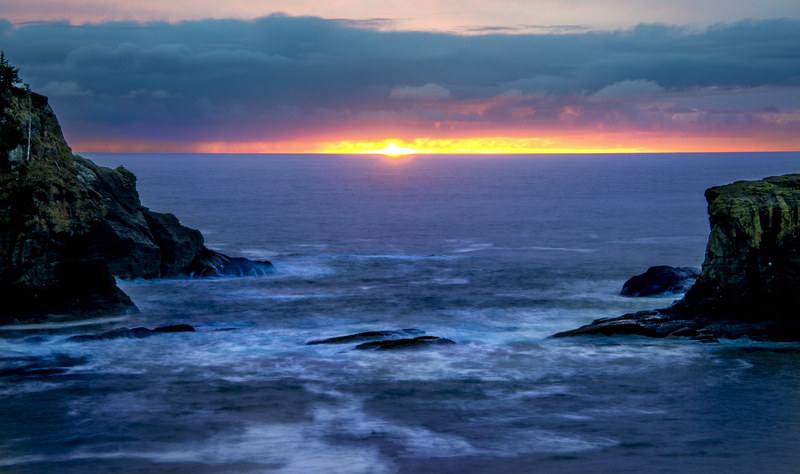 Wide panoramic long exposure of sunset fireline framed between coastal rock formations at Cape Flattery